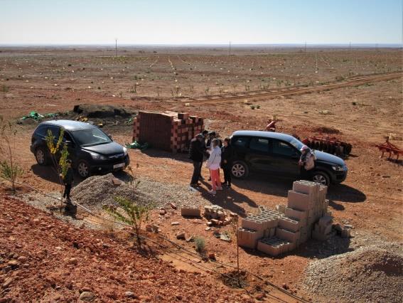 Figure 4: In the photo above, beyond the cars are rows of new trees stretching into the distance. In the foreground are pipes carrying water from the irrigation building. Behind the camera is the reservoir.