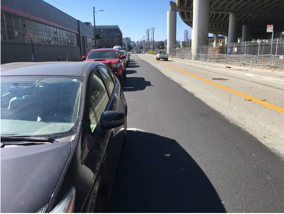 Figure 7: View of intersection with stop sign where drivers’ view of oncoming traffic is blocked by parked cars in former curb lane.
